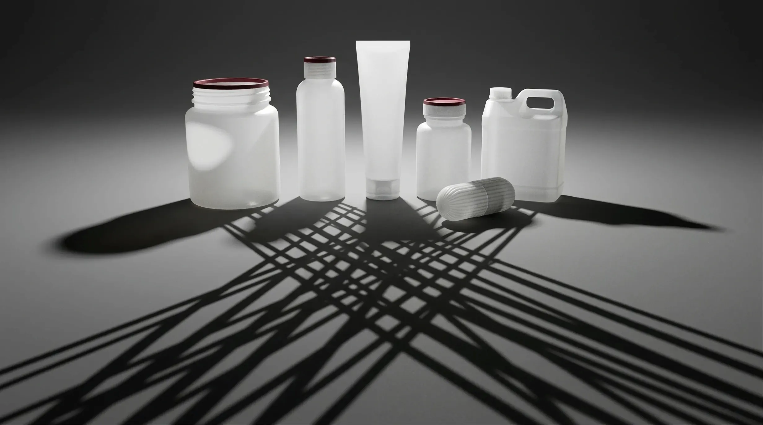 Contenants en plastique blanc de formes variées, dont les ombres portées se croisent au premier plan